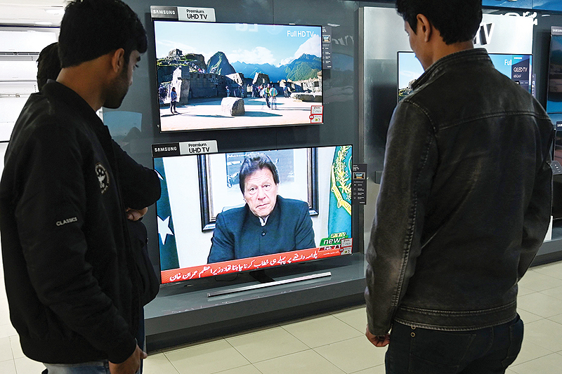 ISLAMABAD: People watch as Pakistani Prime Minister Imran Khan speaks to the nation yesterday about the suicide bombing in Indian-administered Kashmir. — AFP