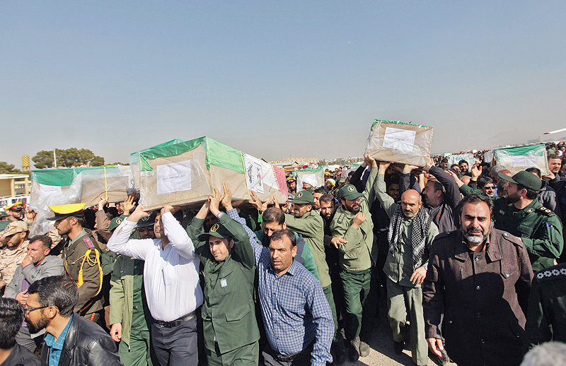 ISFAHAN: Iranians carry the coffins of victims of a suicide car bombing on a Revolutionary Guards bus in southeastern Iran the day before, upon their arrival at Badr airport in Isfahan, some 400 kilometers south of the capital Tehran. _ AFP 