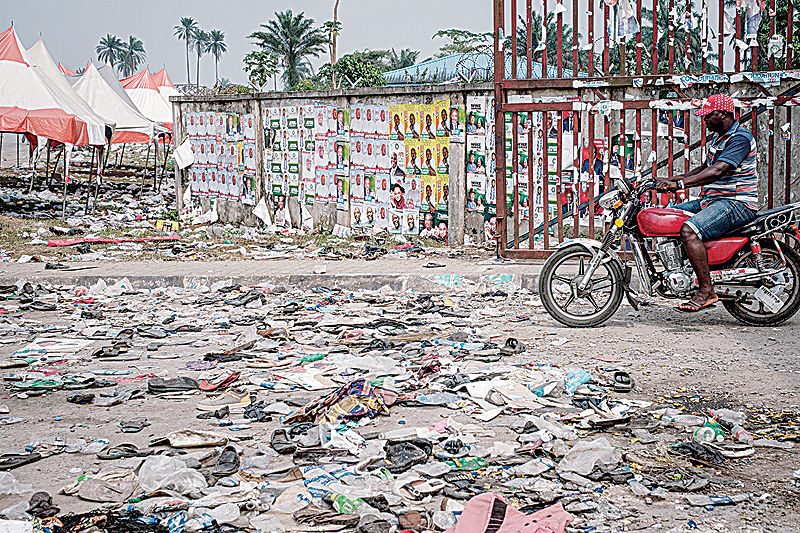 PORT HARCOURT: A biker rides next to shoes and items lying on the ground in front of the main entrance of the Adokiye Amiesimaka Stadium where fifteen people were killed in a stampede during an election campaign rally. —AFP
