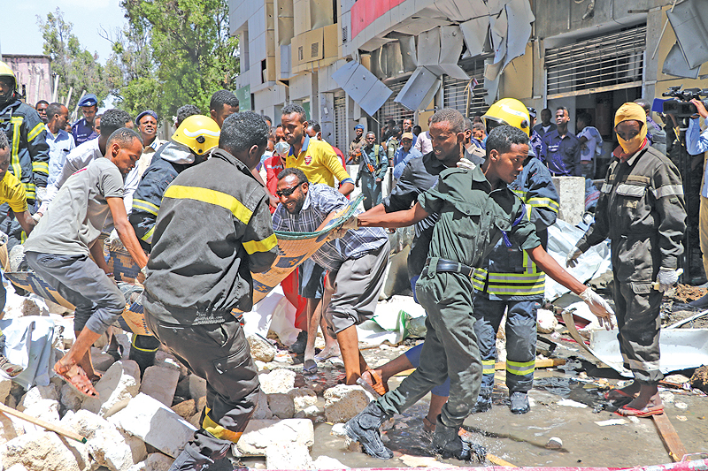 MOGADISHU: Emergency rescue staffs carry the body of a victim over rubble at the scene of a car-bomb attack. - AFP 