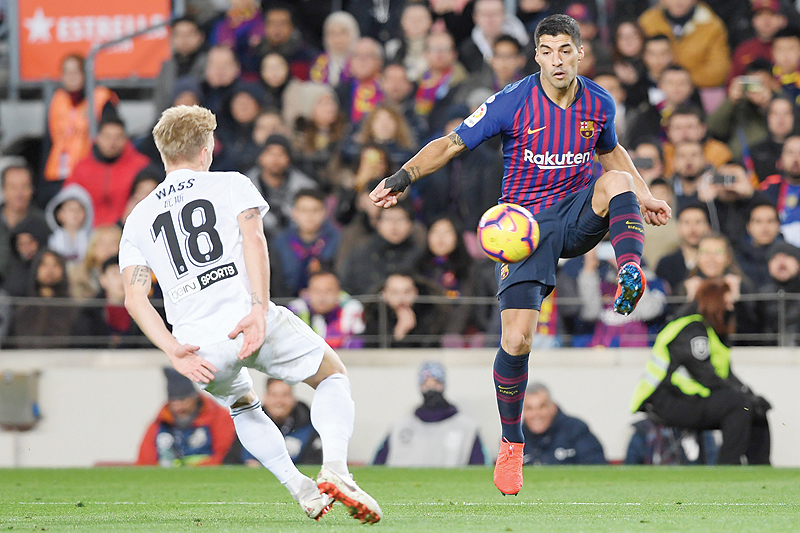BARCELONA: Barcelona's Uruguayan forward Luis Suarez (R) vies for the ball with Valencia's Danish midfielder Daniel Wass during the Spanish league football match FC Barcelona against Valencia CF at the Camp Nou stadium in Barcelona on Saturday. - AFP