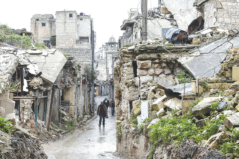 ALEPPO: Syrian people walk amid destruction in the Bab Al-Qinnasrin area in Aleppo’s Old city. — AFP