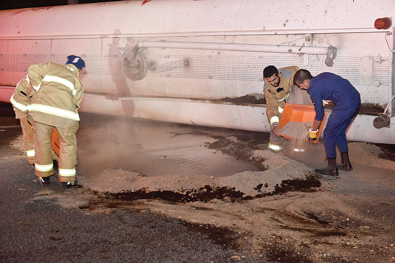 KUWAIT: Firefighters pour sand on fuel that spilled from a truck which was involved in an accident on King Fahd Road, to prevent it from catching fire