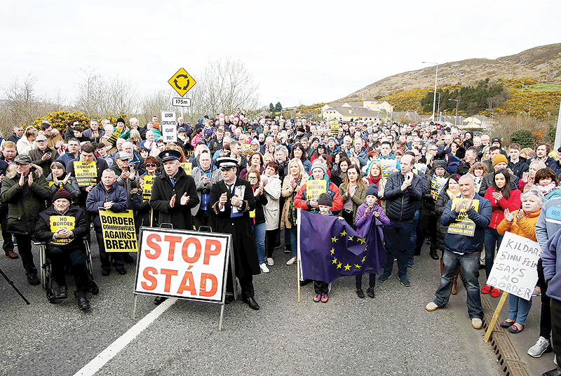 CARRICKCARNAN: Protesters against any border between Ireland and Northern Ireland because of Brexit hold placards at the Carrickcarnan border between Newry in Northern Ireland and Dundalk in the Irish Republic. — AFP