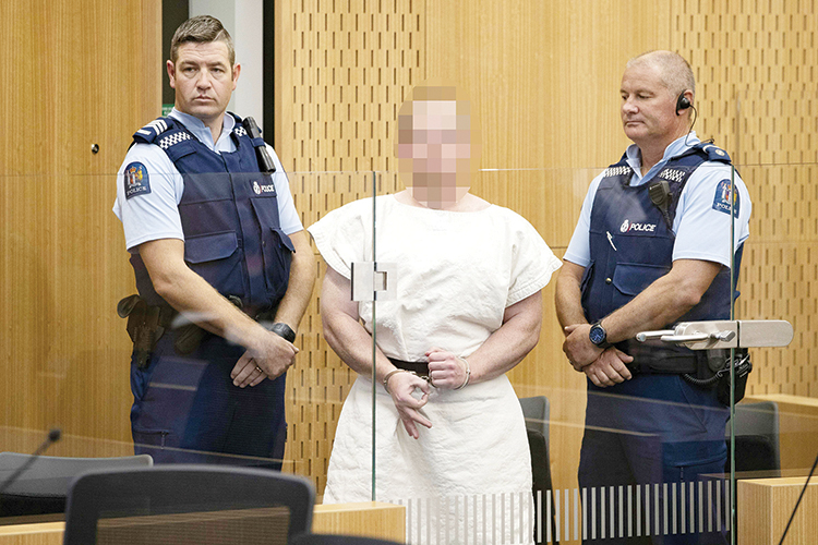 TOPSHOT - Brenton Tarrant, the man charged in relation to the Christchurch massacre,  makes a sign to the camera during his appearance in the Christchurch District Court on March 16, 2019. - A right-wing extremist who filmed himself rampaging through two mosques in the quiet New Zealand city of Christchurch killing 49 worshippers appeared in court on a murder charge March 16, 2019. Australian-born 28-year-old Brenton Tarrant appeared in the dock wearing handcuffs and a white prison shirt, sitting impassively as the judge read a single murder charge against him. A raft of further charges are expected. (Photo by Mark Mitchell / POOL / AFP) / EDS NOTE HIS FACE MUST BE PIXELATED..ONLY HIS FACE--
