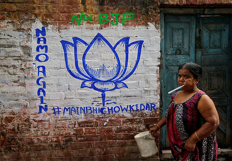 A woman walks past a wall painted with the election symbol of India's ruling Bharatiya Janata Party (BJP) in an alley at a residential area in Kolkata, India, March 22, 2019. Picture taken March 22, 2019. REUTERS