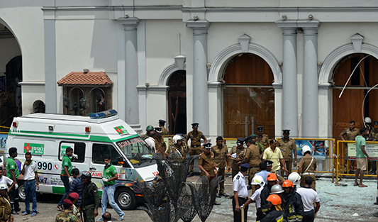 An ambulance is seen outside the church premises with gathered security personnel following a blast at the St. Anthony's Shrine in Kochchikade, Colombo on April 21, 2019. - At least 42 people were killed April 21 in a string of blasts at hotels and churches as worshippers attended Easter services, a police official told AFP. (Photo by ISHARA S. KODIKARA / AFP)
