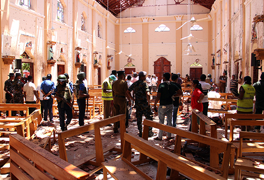 Sri Lankan security personnel walk through debris following an explosion in St Sebastian's Church in Negombo, north of the capital Colombo, on April 21, 2019. - A series of eight devastating bomb blasts ripped through high-end hotels and churches holding Easter services in Sri Lanka on April 21, killing nearly 160 people, including dozens of foreigners. (Photo by STR / AFP)