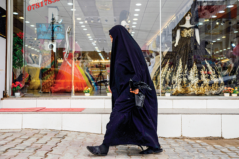DIWANIYAH, Iraq: An woman walks past a dress shop in the central Iraqi city of Diwaniya. Iraqi society remains largely conservative, bound by tribal traditions and religious customs practiced from its sprawling capital Baghdad to far-flung rural provinces. — AFP