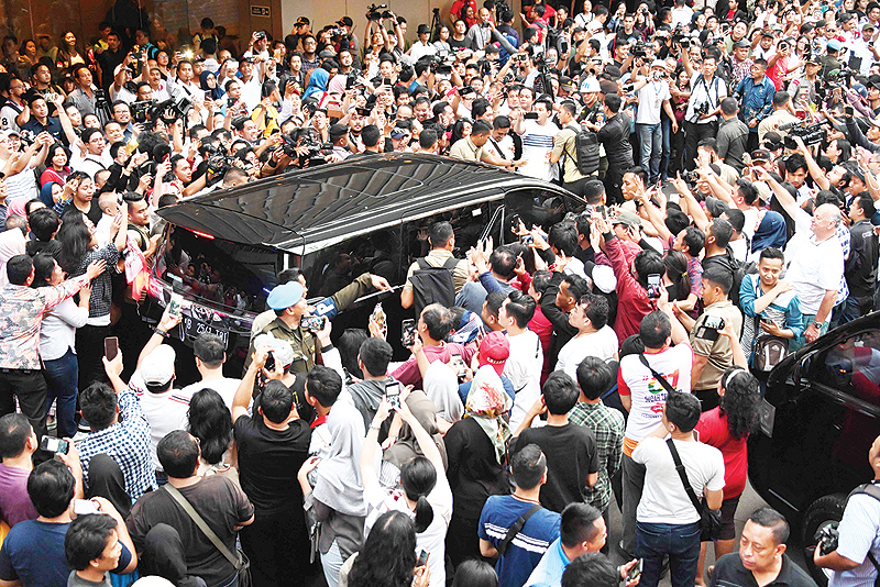 JAKARTA: Supporters surround a vehicle carrying Indonesian President Joko Widodo after the country’s general election in Jakarta yesterday. Widodo was on track to be re-elected as president of the world’s third-biggest democracy, with pollsters giving him a wide lead over rival Prabowo Subianto, an ex-general. — AFP