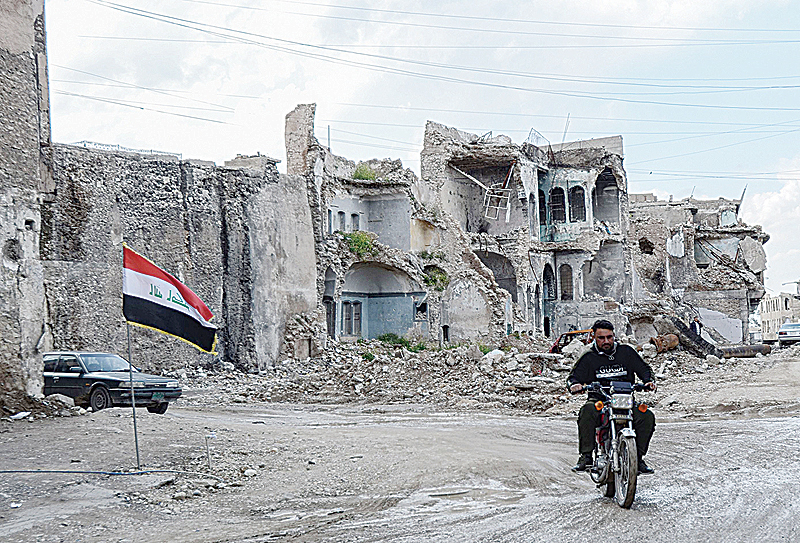 MOSUL: A man rides a motorcycle among devastated buildings in the old city of Mosul in northern Iraq. —AFP