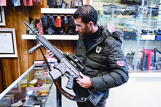 A customer inspects a rifle sold in a gun shop in the northern Iraqi city of Mosul on January 28, 2019. - Hunting rifles, pistols and towers of ammunition magazines: gunstores are popping up in Mosul, where residents are keen to own personal firearms in the unpredictable aftermath of jihadist rule.nThe Islamic State (IS) group reigned over the city for three years before being ousted by Iraqi forces in mid-2017. (Photo by Zaid AL-OBEIDI / AFP)