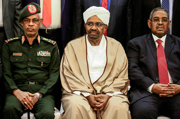 (FILES) In this file photo taken on March 14, 2019 Sudan's President Omar al-Bashir (C) sits among his Defence Minister Awad Ibnouf (L) and Prime Minister Mohamed Tahir Eila (R) as they pose for a group photo with members of the new 20-member cabinet taking oath at the presidential palace in Khartoum. - Sudanese President Omar al-Bashir has been removed from power and detained by the country's army, Defence Minister Awad Ibnouf announced on state television on April 11, 2019. Bashir, who ruled with an iron-fist since he swept to power in an Islamist-backed coup in 1989, has been removed after months of deadly protests across the country. (Photo by ASHRAF SHAZLY / AFP)