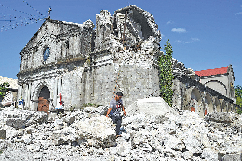 PORAC, Philippines: A church worker walks past rubble of the 18th century St Catherine of Alexandria after its bell tower was destroyed following a 6.3 magnitude earthquake that struck the town of Porac, pampanga province yesterday. — AFP