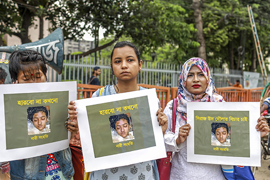 In this photo taken on April 12, 2019 Bangladeshi women hold placards and photographs of schoolgirl Nusrat Jahan Rafi at a protest in Dhaka, following her murder by being set on fire after she had reported a sexual assault. - A schoolgirl was burned to death in Bangladesh on the orders of her head teacher after she reported him for sexually harassing her, police said April 19. The death of 19-year-old Nusrat Jahan Rafi last week sparked protests across the South Asian nation, with the prime minister promising to prosecute all those involved. (Photo by SAZZAD HOSSAIN / AFP)