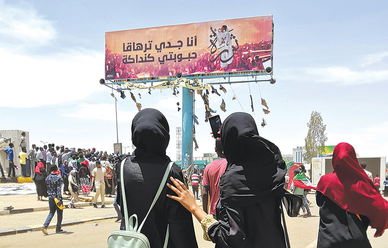 KHARTOUM: A woman takes a photograph with her smarphone of a billboard showing a reproduction of a picture of Alaa Salah, a Sudanese woman who has become an icon of the protest movement after a video of her leading demonstrators’ chants went viral. — AFP