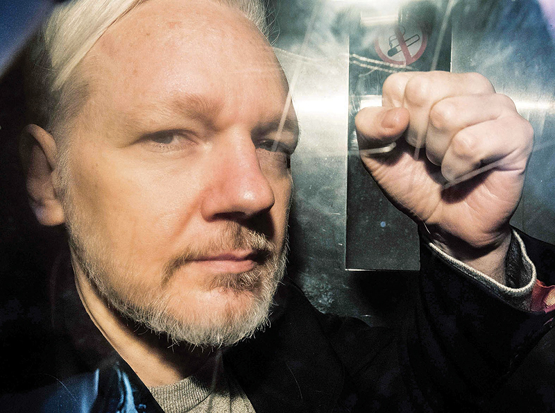 LONDON: WikiLeaks founder Julian Assange gestures from the window of a prison van as he is driven into Southwark Crown Court yesterday. - AFP 