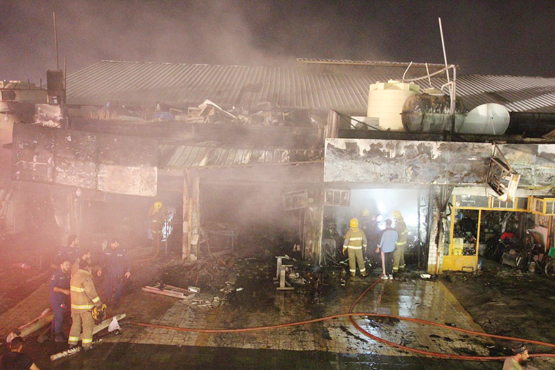 KUWAIT: Firefighters battle a blaze at car repair shops in Shuwaikh Industrial.