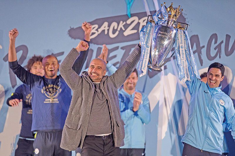 nMANCHESTER: Manchester City's Spanish manager Pep Guardiola (C), Manchester City assistant coach Mikel Arteta (R) and Manchester City's Belgian defender Vincent Kompany (L) show the Premier League trophy to supporters outside the Etihad Stadium in Manchester. - AFPnnnn