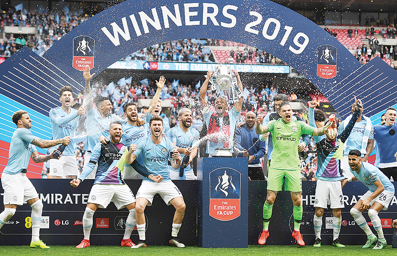 LONDON: Manchester City's Belgian captain Vincent Kompany (C) lifts the winner's trophy as the players celebrate victory after the English FA Cup final football match between Manchester City and Watford at Wembley Stadium in London. Manchester City beat Watford 6-0 at Wembley to claim the FA Cup. - AFP