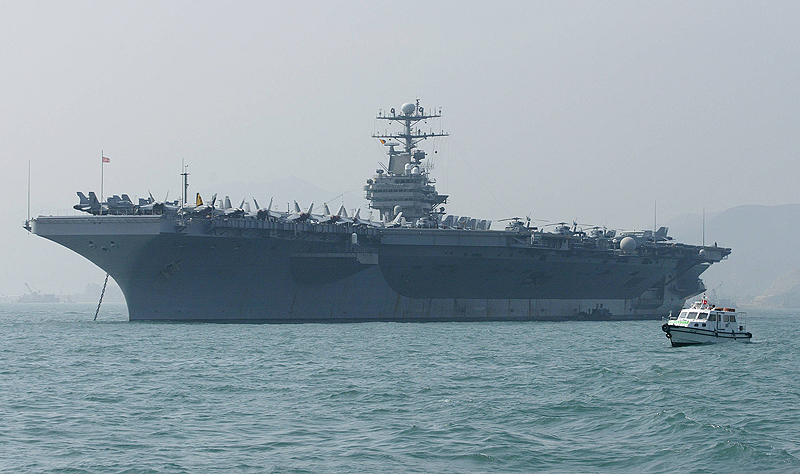 HONG KONG: In this file photo, a small boat sails by the USS Abraham Lincoln moored in Hong Kong. The United States is sending an aircraft carrier strike group and a bomber task force to the Middle East in a 'clear and unmistakable' message to Iran. - AFP n