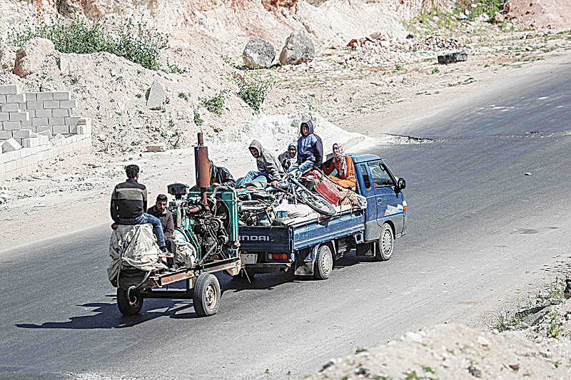 IDLIB, Syria: Residents flee with their belongings from regime shelling in the southern countryside of this province yesterday. —AFP