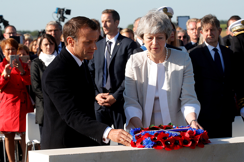 French President Emmanuel Macron and British Prime Minister Theresa May lay a wreath of flowers during a ceremony to lay the first stone of the British Normandy Memorial in Ver-sur-Mer, Normandy, northwestern France, on June 6, 2019, as part of D-Day commemorations marking the 75th anniversary of the World War II Allied landings in Normandy. (Photo by PHILIPPE WOJAZER / POOL / AFP)