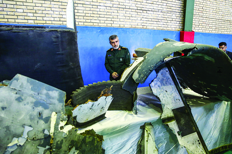 TOPSHOT - General Amir Ali Hajizadeh (C), Iran's Head of the Revolutionary Guard's aerospace division, looks at debris from a downed US drone reportedly recovered within Iran's territorial waters and put on display by the Revolutionary Guard in the capital Tehran on June 21, 2019. - Iran's state television broadcast images of what it said was debris from a downed US drone recovered inside its territorial waters. The television broadcast a short clip of a Revolutionary Guards general answering questions in front of some of the debris he said had been recovered after yesterday's missile strike. The downing of the drone -- which Washington insists was over international waters but Tehran says was within its airspace -- has seen tensions between the two countries spike further after a series of attacks on tankers the US has blamed on Iran. (Photo by Meghdad Madadi / TASNIM NEWS / AFP)