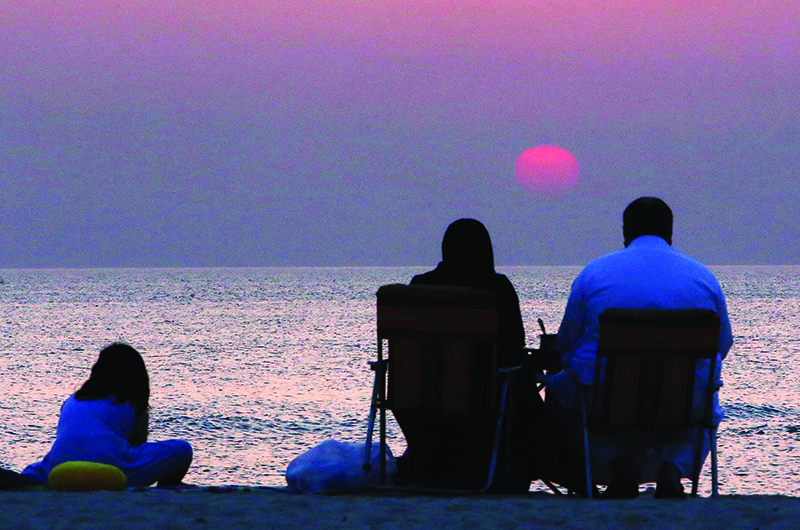 A family watches the sunrise on the beach in Kuwait City on the last day of the Eid al-Fitr's long weekend, marking the end of the Muslim holy month of Ramadan, on June 8, 2019. - Temperatures in the Gulf emirate have soared this week reaching the unusual record of 48 degrees Celsius for June at mid-day. (Photo by Yasser Al-Zayyat / AFP)