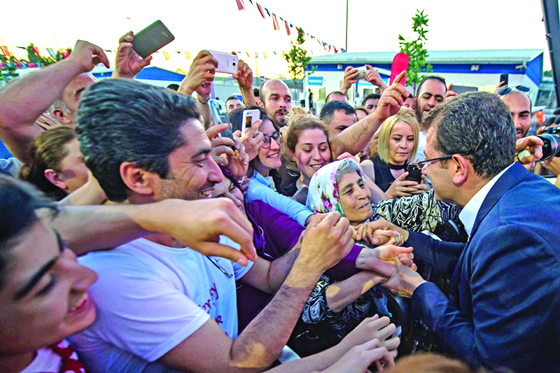 Ekrem Imamoglu (R), Istanbul mayoral candidate of the main opposition Republican People's Party (CHP), chat with supporters during a election campain at Zeytinburnu district in Istanbul on May 29, 2019. - He says he does not much like fighting, preaches reconciliation rather than confrontation, and campaigns through social media rather than television. That approach has made Ekrem Imamoglu, the opposition candidate in this week's re-run vote for Istanbul mayor, the antithesis of the man who has dominated Turkish politics for much of the past two decades: President Recep Tayyip Erdogan. Throughout his career, Erdogan has made a virtue of political street-fighting, often accusing opponents of links to terror groups or seeking to undermine the country. (Photo by Yasin AKGUL / AFP)