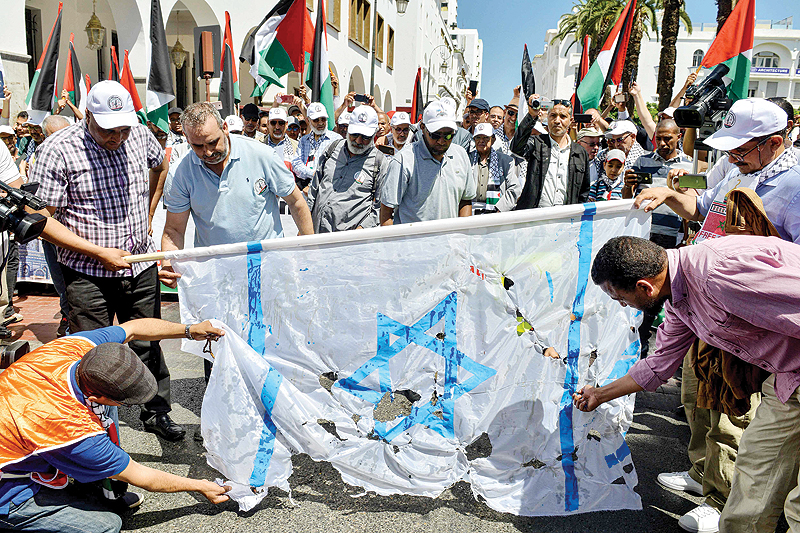 RABAT: Protesters tear a makeshift Israeli flag during a protest in the Moroccan capital yesterday against a US-led economic conference in Bahrain with its declared aim of achieving Palestinian prosperity. – AFP 
