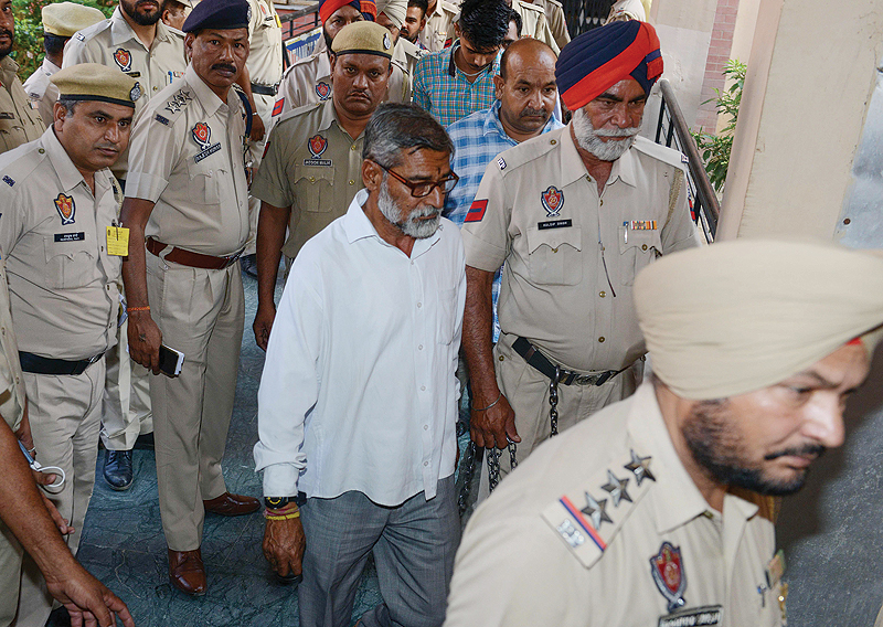 PATHANKOT, India: Indian Punjab Police escort Sanji Ram (center), accused for the rape and murder of an eight-year-old girl in Kathua in Jammu and Kashmir, as he comes out of court yesterday. — AFP