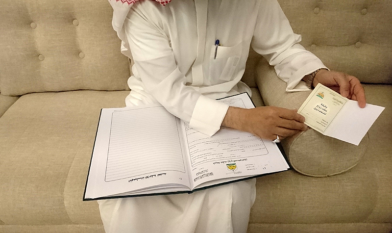 RIYADH: Saudi cleric Abdulmohsen Al-Ajemi shows samples of wedding contracts during an interview with AFP on June 19, 2019. - AFP 