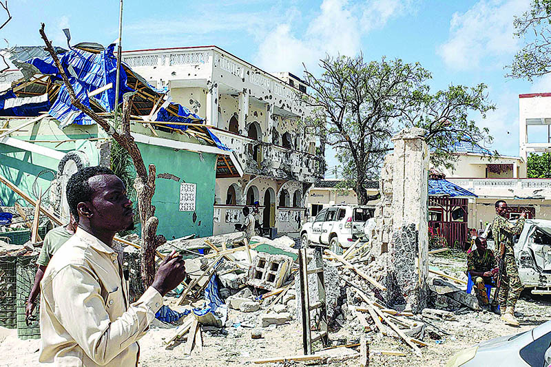 TOPSHOT - A man passes in front of the rubbles of the popular Medina hotel of Kismayo on July 13, 2019, a day after at least 26 people, including several foreigners, were killed and 56 injured in a suicide bomb and gun attack claimed by Al-Shabaab militants. - A suicide bomber rammed a vehicle loaded with explosives into the Medina hotel in the port town of Kismayo before several heavily armed gunmen forced their way inside, shooting as they went, authorities said. (Photo by - / AFP)