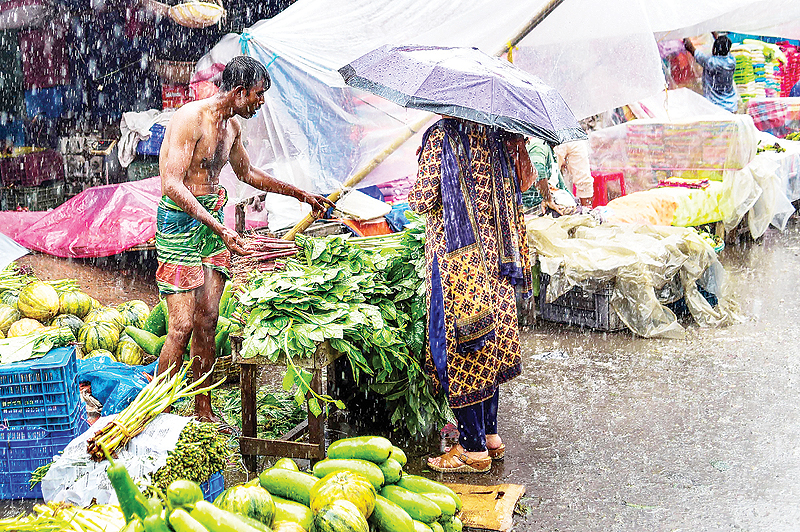 DHAKA: A Bangladeshi street vendor sells vegetables under heavy rain in Dhaka. The monsoon rains sweeps across the subcontinent from June to September. —AFP