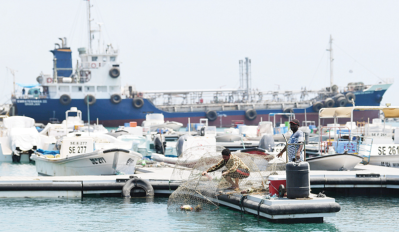 FUJAIRAH: Fishermen are pictured in front of ships docked in the port of Fujairah yesterday in the east of the United Arab Emirates (UAE), as recent tensions spiraling between Iran and the United States have affected movement in the Gulf near the strategic Strait of Hormuz. —AFP