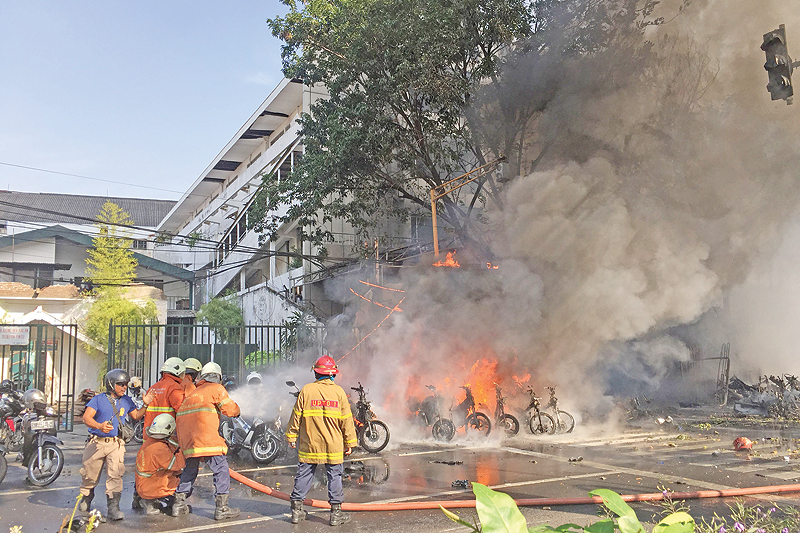 SURABAYA: This file handout photo shows firefighters trying to extinguish a fire after a blast outside the Gereja Pantekosta Pusat Surabaya in Surabaya. — AFP
