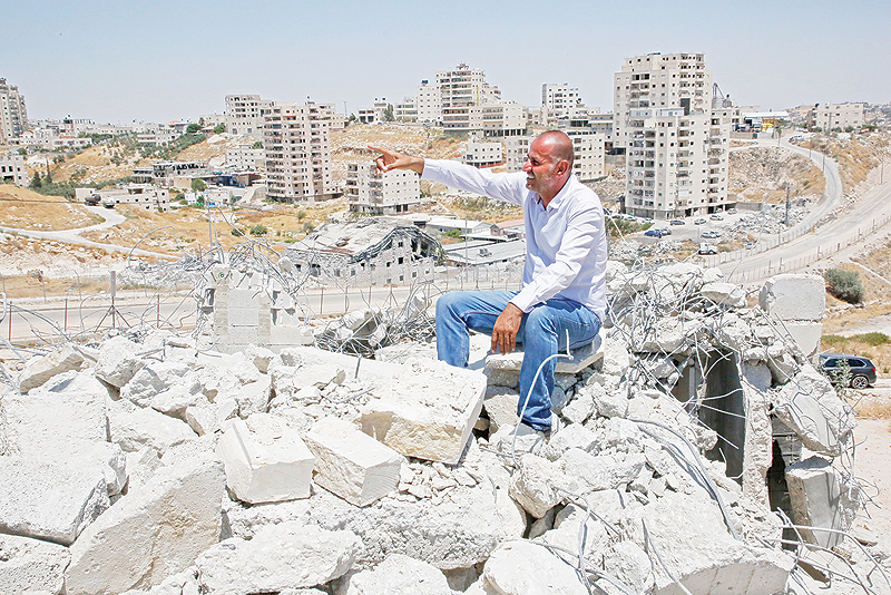 DAR SALAH: A picture taken in Dar Salah on Wednesday shows Akram Zwahreh sitting on top of the rubble of his house during a tour for Fatah Movement to the site of demolished buildings in the West Bank, adjacent to the area of Sur Baher in East Jerusalem. — AFP