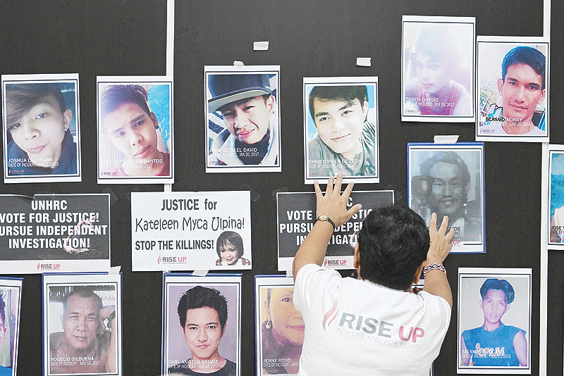 MANILA: A relative of a victim of an extrajudicial killing touches the portrait of the relatives during a memorial mass at the Philippine Human Rights Commission office in Manila. — AFP