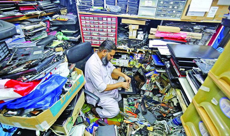 Mohamad Abid Othman, 50, from Pakistan, repairs a laptop computer inside his shop in Kuwait City in August 19, 2019. Othman started reparing laptops as a hobby before he opened a used PC repairs shop in Kuwait, where he has been working for nearly 30 years.