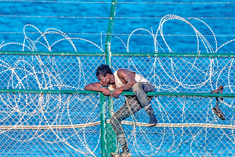 TOPSHOT - CORRECTION - A migrant forces his way into the Spanish territory of Ceuta on August 30, 2019. Over 150 migrants made their way into Ceuta after storming a barbed-wire border fence with Morocco (Photo by Antonio SEMPERE / AFP) / ìThe erroneous mention[s] appearing in the metadata of this photo by Antonio SEMPERE has been modified in AFP systems in the following manner: [August 30, 2019] instead of [August 30, 2018]. Please immediately remove the erroneous mention[s] from all your online services and delete it (them) from your servers. If you have been authorized by AFP to distribute it (them) to third parties, please ensure that the same actions are carried out by them. Failure to promptly comply with these instructions will entail liability on your part for any continued or post notification usage. Therefore we thank you very much for all your attention and prompt action. We are sorry for the inconvenience this notification may cause and remain at your disposal for any further information you may require.î