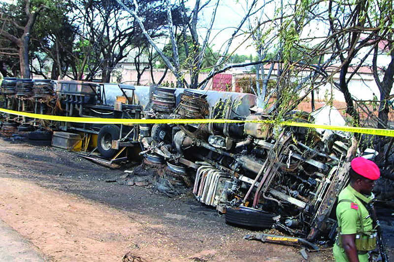 Police tape cordons off the area where the carcass of a burnt out fuel tanker is seen along the side of the road following an explosion on August 10, 2019, in Morogoro, 200 kilometres (120 miles) west of the Tanzanian capital Dar es Salaam. - At least 60 people perished in Tanzania when a fuel tanker overturned and then exploded as crowds of people rushed to syphon off leaking fuel. The deadly blast, which took place near the town of Morogoro, west of the economic capital Dar es Salaam, is the latest in a series of similar disasters in Africa. (Photo by STRINGER / AFP)