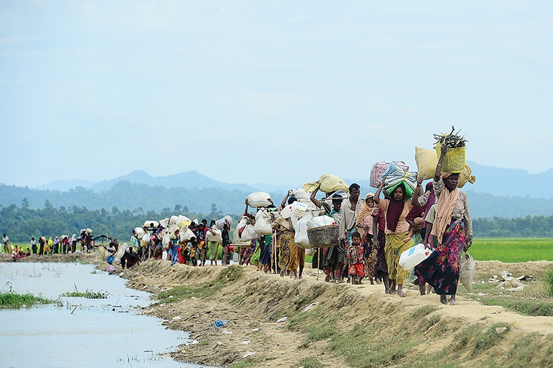 (FILES) In this file photo taken on October 19, 2017 Rohingya refugees who were stranded walk near the no man's land area between Bangladesh and Myanmar in the Palongkhali area next to Ukhia. - Some 200,000 Rohingya rallied in a Bangladesh refugee camp on August 25, 2019 to mark two years since they fled a violent crackdown by Myanmar forces, just days after a second failed attempt to repatriate the refugees. (Photo by Munir UZ ZAMAN / AFP)
