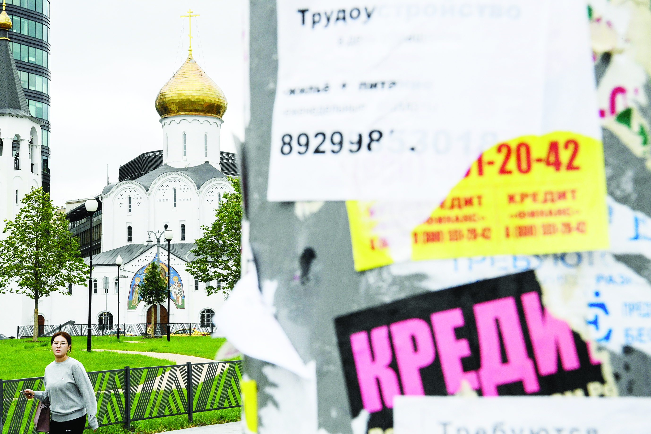 A woman passes a notice advertising loans, with a church seen in the background, in downtown Moscow on August 14, 2019. (Photo by Kirill KUDRYAVTSEV / AFP)