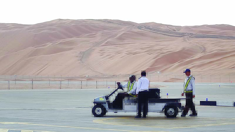 (FILES) In this file photo taken on May 10, 2016, Aramco staff members stand on the tarmac at the Saudi Aramco airport surrounded by sand dunes by the Shaybah oilfield, some 800 kilometers (500 miles) southeast of the eastern oil centre of Dhahran. - A Yemeni rebel attack sparked a fire in a Saudi gas plant on August 17, 2019 but caused no casualties or disruption to production, state-owned energy company Saudi Aramco said. (Photo by IAN TIMBERLAKE / AFP)