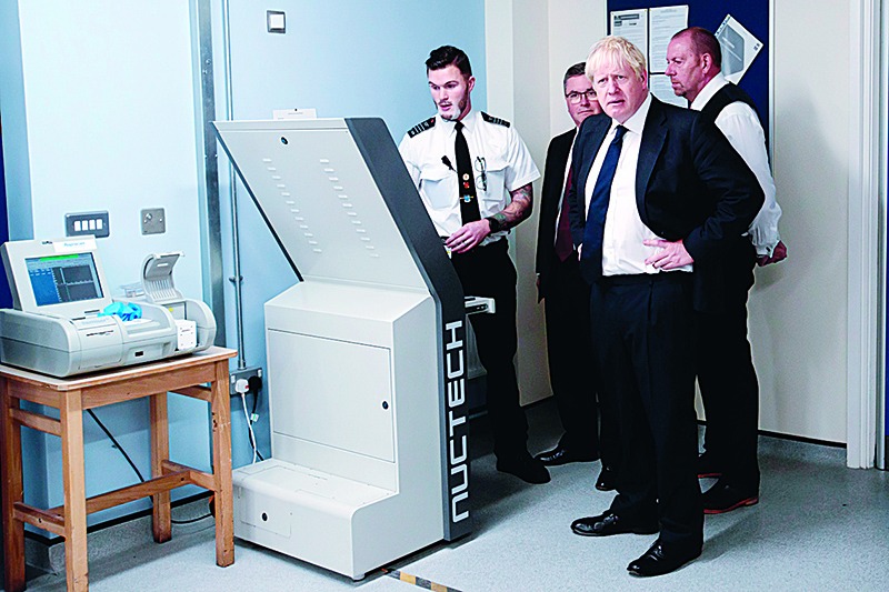 Britain's Prime Minister Boris Johnson (2R), Britain's Justice Secretary and Lord Chancellor Robert Buckland (2L), and Governor of HMP Leeds Steve Robson (R), are shown a torso and body scanner by a member of prison staff during a visit to HM Prison Leeds, a Category B men's prison in Leeds, northern England, on August 13, 2019. (Photo by Jon Super / POOL / AFP)