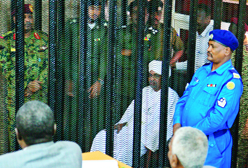 Sudan's deposed military ruler Omar al-Bashir sits in a defendant's cage during the opening of his corruption trial in Khartoum on August 19, 2019. - Bashir has admitted to receiving $90 million in cash from Saudi monarchs, an investigator told a Khartoum court today. (Photo by Ebrahim HAMID / AFP)