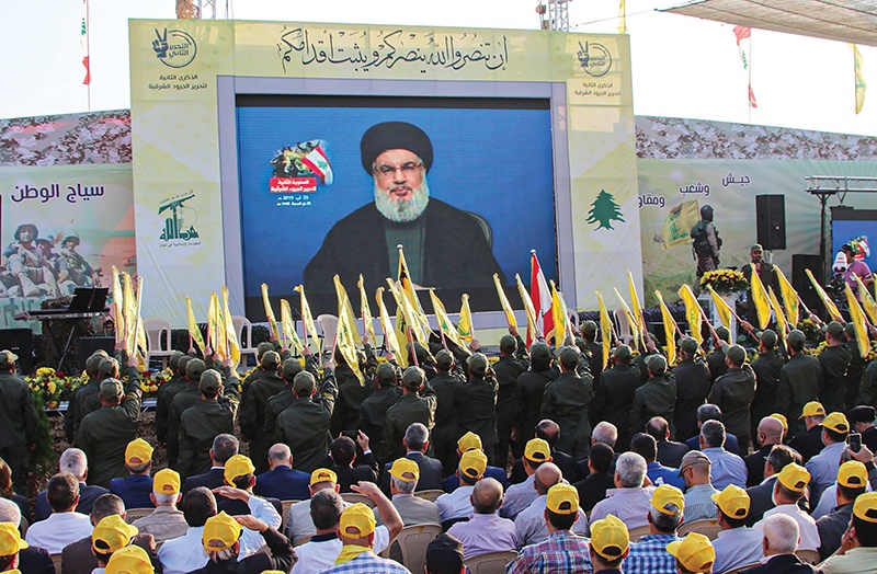 Sympathisers of the Shiite Hezbollah movement gather to watch the transmission on a large screen of a speech by the movement's leader Hasan Nasrallah, in the town of Al-Ain in Lebanon's Bekaa valley on August 25, 2019, during a gathering event organised by the group. (Photo by - / AFP)