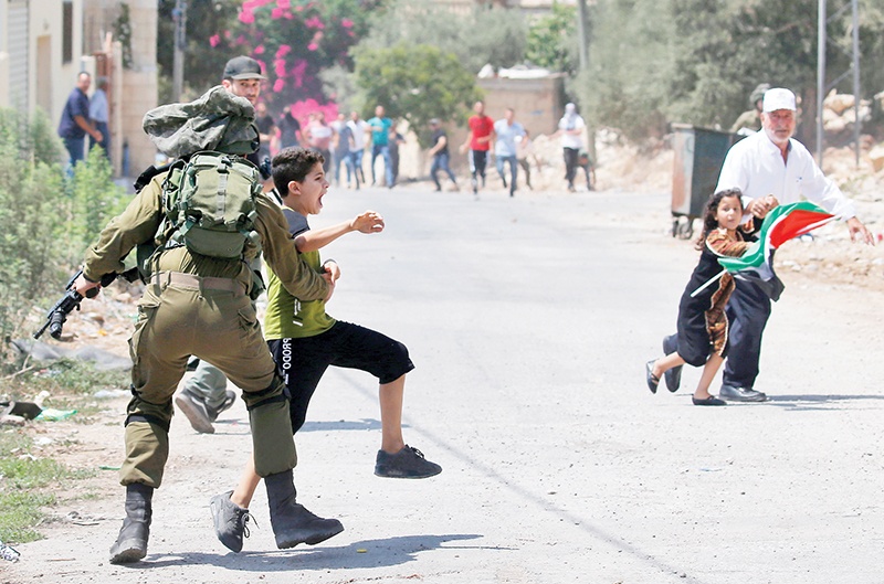 An Israeli soldier temporarily detains a Palestinian youth during clashes following a weekly protest against the expropriation of Palestinian land by Israel, in the village of Kfar Qaddum, in the Israeli-occupied West Bank on August 23, 2019. (Photo by JAAFAR ASHTIYEH / AFP)