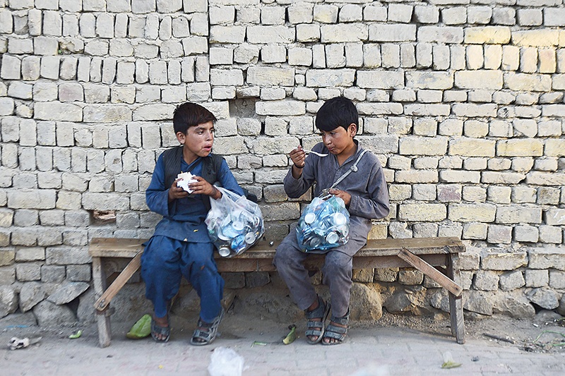 In this photograph taken on August 28, 2019, Afghan child labourers take a break to eat soup after collecting recyclable materials from the garbage in Mazar-i-Sharif. (Photo by FARSHAD USYAN / AFP)